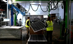 Des employées de l'entreprise Envie 2E passent dans une machine un panneau solaire usagé pour le recyclage de ses piÚces, le 13 novembre 2023 à Saint-LoubÚs, en Gironde