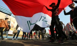 Des manifestants irakiens soulèvent un drapeau sur la place Tahrir à Bagdad, le 22 décembre 2019