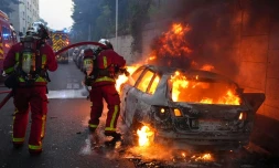 Des pompiers tentent d'éteindre une voiture en feu en marge d'une manifestation à Nanterre, théùtre d'incidents en soirée, le 27 juin 2023