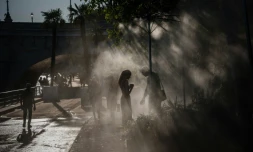 Des personnes se rafraĂźchissent sous des brumisateurs Ă Paris, le 10 juillet 2026