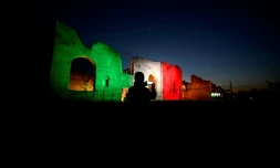 Un homme prend une photo des Thermes de Caracalla sur lesquels les couleurs du drapeau italien sont projetées, le 10 avril 2020 à Rome