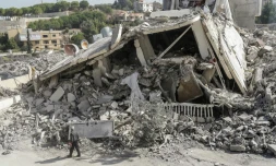 Un homme marche devant les décombres d'un bùtiment détruit par une frappe israélienne dans le village de Zeita, au sud de Beyrouth, le 14 octobre 2024, sur fond de guerre entre le Hezbollah libanais et Israël