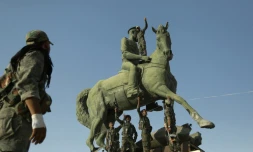 Des combattants kurdes de l'YPG et la police posent sous une statue de Basel al-Assad, frÚre du président syrien, à Hassaké le 23 août 2016
