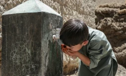 Un enfant boit de l'eau au robinet d'une fontaine à Qavariyak, dans la province de Bamiyan, le 18 juin 2025 en Afghanistan