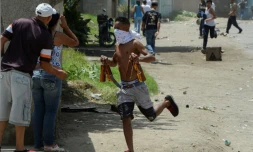Un pillard s'enfuit avec des bouteilles de bière volées dans un magasin mis à sac à Maracay, le 27 juin 2017.