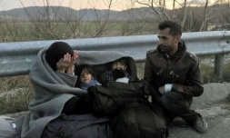 Une famille de réfugiés attend de passer la frontiÚre entre la GrÚce et la Macédoine, prÚs du village grec d'Idomeni, dans la nuit du 21 février 2016