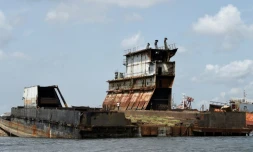Un homme marche sur une épave d'un bateau abandonné dans le port de Lagos le 8 avril 2019.