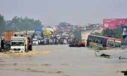 Des personnes se tiennent sur un pont aérien sur une route nationale inondée après le débordement de la rivière Kosi suite à de fortes pluies près de Rampur dans l'État indien de l'Uttar Pradesh, le 20 octobre 2021