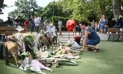 Une femme dépose des fleurs en hommage aux victimes d'une attaque au couteau à Annecy, le 9 juin 2023 aux "Jardins de l'Europe" de la ville, dans les Alpes françaises