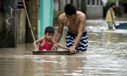 Un père pousse son fils dans une bassine dans une rue inondée par le typhon Mangkhut à Bulacan, aux Philippines, le 16 septembre 2018.