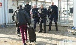 Un migrant se dirige vers des policiers à l'entrée de la "Jungle" de Calais, le 23 octobre 2016