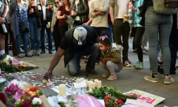 Un homme et sa petite fille allument des bougies à quelques pas du lieu de l'attentat à l'Albert Square de Manchester le 23 mai 2017