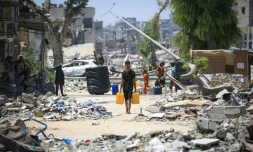 Un Palestinien porte des bidons d'eau, dans les ruines de Khan YounĂšs, dans le sud de la bande de Gaza, le 11 juin 2024