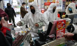 Des employés en pharmacie, en combinaison et masque de protection, servent des clients, le 25 janvier 2020 à Wuhan, épicentre du nouveau coronavirus