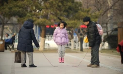 Une petite fille joue à la corde à sauter avec sa famille à Pékin, le 7 décembre 2012