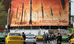 Des automobilistes passent devant un panneau d'affichage représentant des missiles balistiques iraniens, dans le centre de Téhéran, le 15 avril 2024