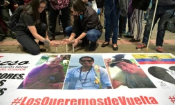 Des proches des deux journalistes équatoriens Javier Ortega et Paul Rivas et de leur chauffeur Efrain Segarra, alument des bougies près de leurs portraits après l'annonce de leur mort, le 13 avril 2018 à Quito