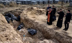 Des prĂȘtres prient devant une fosse commune avec de nouveaux cadavres, dans la petite ville ukrainienne de Boutcha, le 7 avril 2022