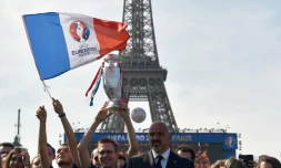 Un supporter tient le drapeau de l'Euro-2016 dans la fan zone au pied de la Tour Eiffel à Paris, tandis que des milliers de personnes se rassemblent pour le concert, le 9 juin 2016