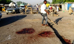 Un Nigérian s'éloigne de la scène d'une attaque suicide qui a fait 13 morts le 23 octobre 2017 à Maiduguri, dans le nord-est du Nigeria