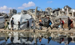 Des palestiniens marchent près des décombres d'un bâtiment effondré dans le quartier de Nasr, à l'ouest de la ville de Gaza, le 15 avril 2025
