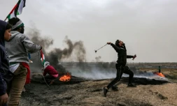 Un Palestinien lance une pierre en direction des soldats israéliens postés de l'autre côté de la barrière frontalière entre la bande de Gaza et Israël, lors du premier anniversaire des "Grandes marches du retour", le 30 mars 2019 à l'est de Gaza city