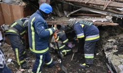 Des membres des services de secours cherchent dans les décombres d'un immeuble, le 8 janvier 2024 à Zmiiv, dans la région de Kharkiv, en Ukraine