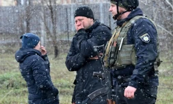 Des personnes se tiennent près d'une fosse commune dans la localité ukrainienne de Boutcha (nord-ouest de Kiev), le 3 avril 2022 