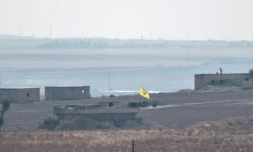 Photo prise depuis le cÎté turc de la frontiÚre turco-syrienne, montrant un drapeau des Unités de protection du peuple (YPG) flottant au-dessus d'un bùtiment prÚs de la ville syrienne de Tal Abyad, le 8 octobre 2019