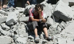 Un jeune garçon est effondré le 21 juillet 2015 sur les décombres de maisons dans un vieux quartier d'Alep, au nord de la Syrie, bombardé par l'aviation syrienne