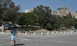 Un touriste se protège de la chaleur, au pied de l'Acropole d'Athènes, fermée aux heures les plus chaudes de la journée en raison d'une canicule exceptionnelle en Grèce, le 2 août 2021