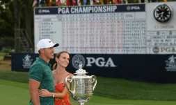 L'Américain Brooks Koepka pose avec sa compagne devant le trophée après sa victoire au Championnat PGA, dernière levée du Grand Chelem, le 12 août 2018 à St Louis (Missouri)