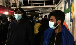 Des migrants avec des masques de protection se préparent à débarquer de l'Ocean Viking au port de Porto Empedocle, en Sicile le 6 juillet 2020