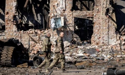 Des soldats ukrainiens devant des immeubles détruits à Trostianets, le 29 mars 2022