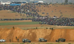 Une photo prise le 30 mars 2018 du côté israélien de la frontière, montre des Palestiniens participant à des manifestations dans la bande de Gaza, sous le regard des militaires israéliens