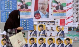 Une femme marche devant des affiches électorales placardées contre un mur de Téhéran en Iran, le 28 février 2024