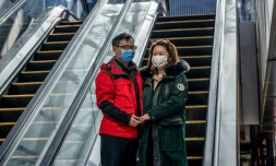 Un couple portant des masques de protection, devant un centre commercial désert, à Pékin le 22 février 2020