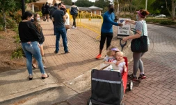 Megan Dominy avec ses deux enfants de quatre et un an, distribue de l'eau et des en-cas aux électeurs qui attendent de pouvoir déposer leurs bulletings lors du vote anticipé pour la présidentielle américaine de 2020, le 24 octobre 2020 à Smyrna