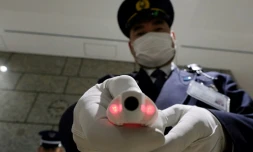 Un agent de sécurité montre un appareil de mesure de la température corporelle, à la réception d'un bâtiment officiel de Tokyo le 5 mars 2020