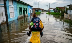 Un homme porte une femme sur son dos dans une zone inondĂ©e de Batabano, le 28 aoĂ»t 2023, lors du passage de la tempĂȘte tropicale Idalia au large de la pointe ouest de Cuba