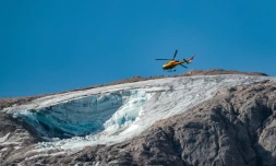 Un hélicoptÚre de secours survole, le 4 juillet 2022, le glacier qui s'est effondré la veille sur la montagne de Marmolada, en Italie