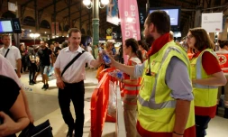 Des membres de la Croix Rouge distribuent de l'eau aux voyageurs coincés dans la soirée à la Gare du Nord, le 19 juillet 2016 à Paris