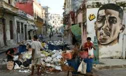 Des Cubains devant un tas d'ordures dans une rue de La Havane, le 23 août 2024