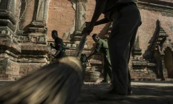 Des soldats pieds nus, comme de coutume dans les temples bouddhistes, ramassent les débris, le 25 août 2016, dans un temple du sanctuaire de Bagan endommagé la veille par un séisme