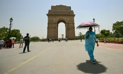 Une passante avec un parasol prĂšs de la porte de l'Inde lors d'une forte canicule Ă New Delhi, le 29 mai 2024