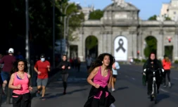 Joggeurs devant la Porte d'Alcala, ornée d'un ruban noir en signe de deuil, le 2 mai 2020 à Madrid