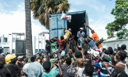 Un homme lance un sac de riz dans la foule lors d'une distribution d'aide humanitaire aux victimes du séisme du 14 août en Haïti, ici aux Cayes le 20 août 2021