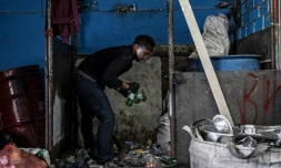 Un homme brise des bouteilles de verre pour les faire recycler, le 25 mai 2022 à Bogota 