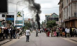 Des Kinois regardent des manifestants brûler des pneus au cours d'une marche anti-Kabila à Kinshasa, le 21 janvier 2018.
