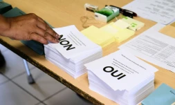Une personne prend les bulletins avant de voter au référendum sur l'indépendance de la Nouvelle-Calédonie, le 4 octobre 2020 dans un bureau à Nouméa